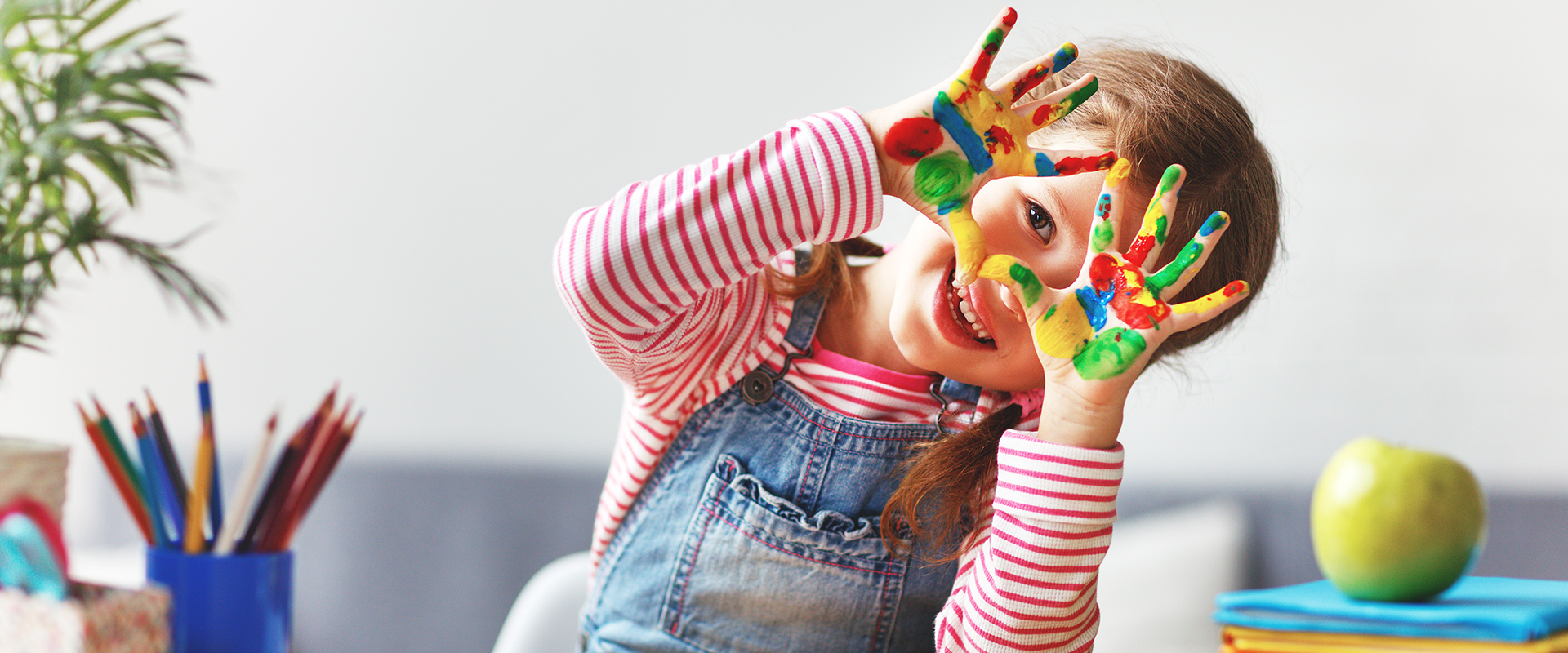 funny child girl draws laughing shows hands dirty with paint